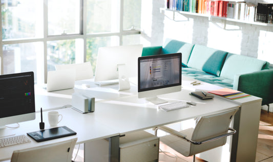 A large collaborative desk, chairs, and other business furniture in a small, modern office